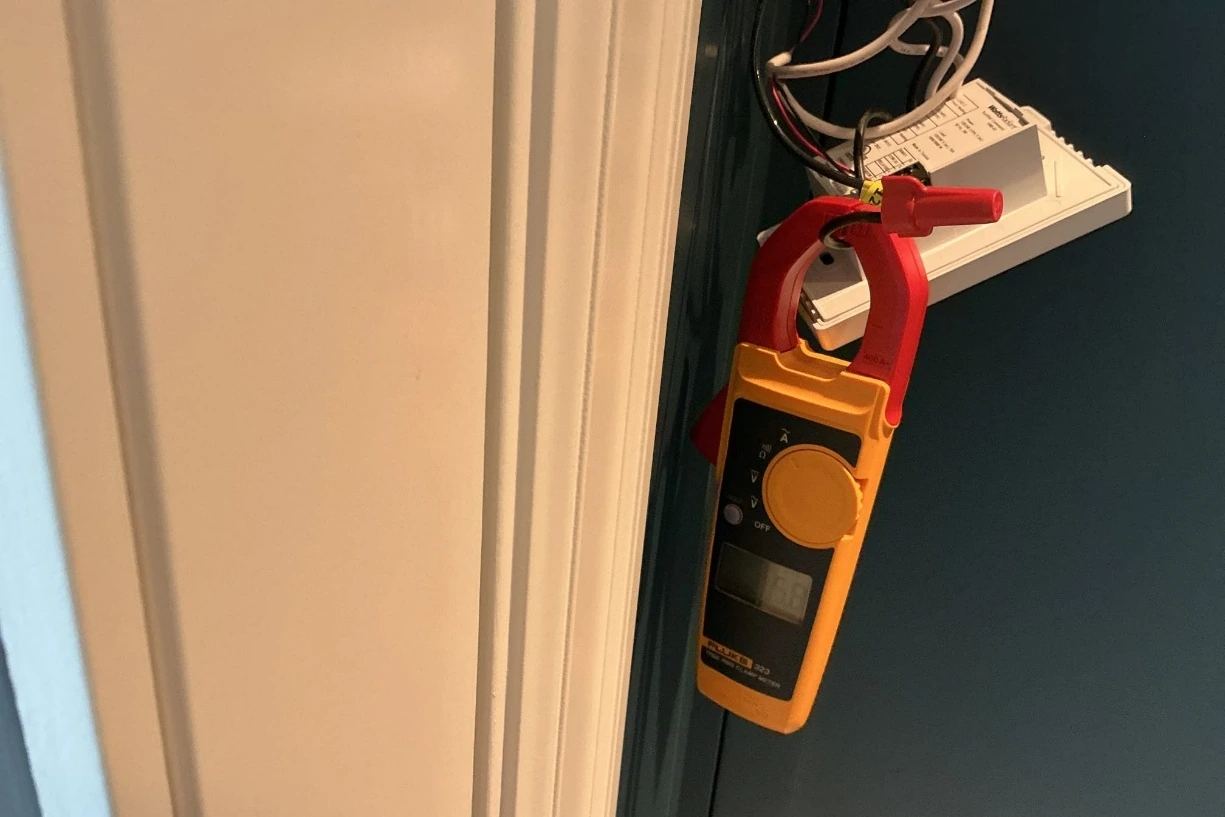 Clamp meter testing the wiring of a heated floor thermostat in a home in Sammamish, WA.