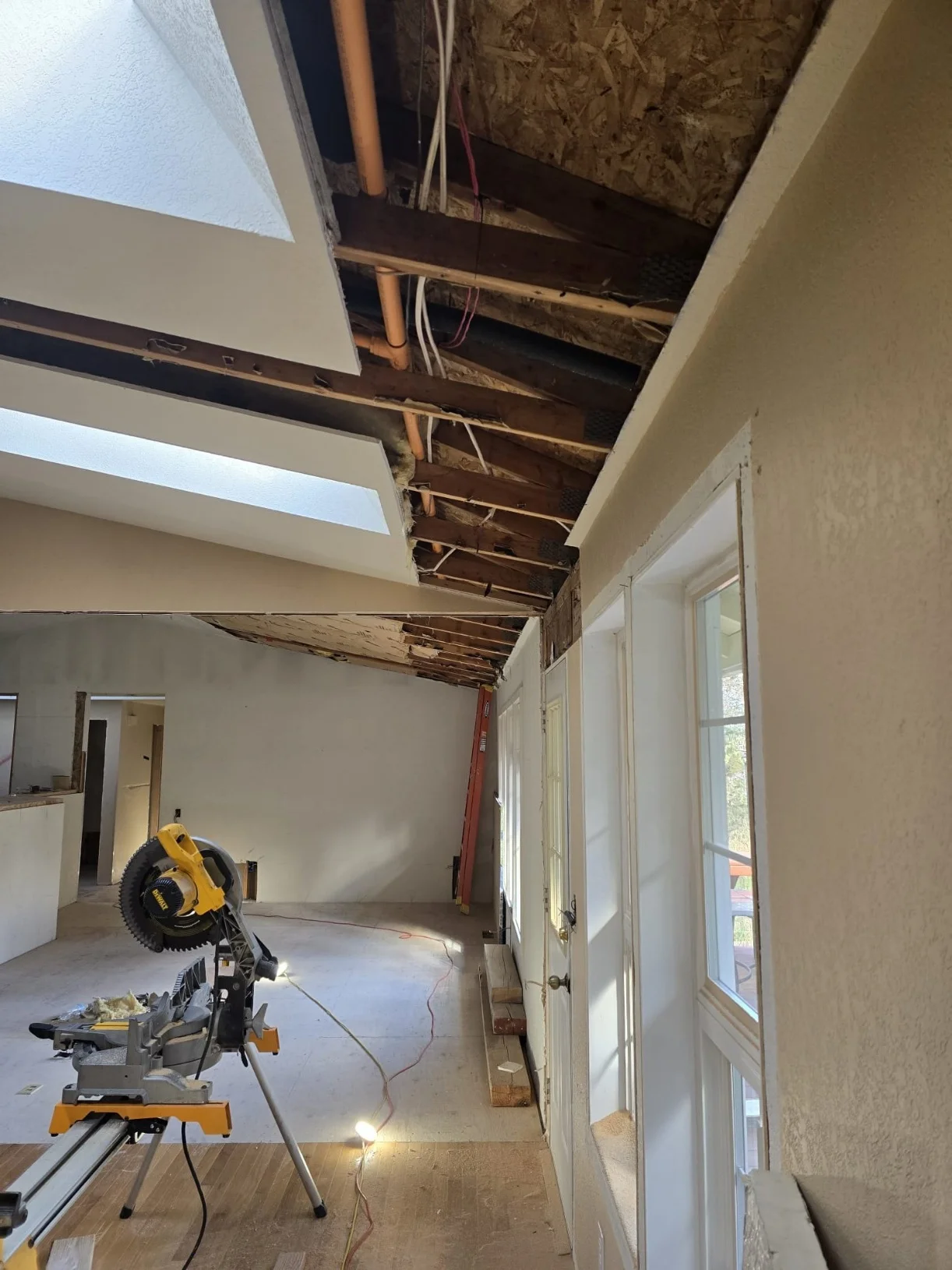 Open ceiling and living-room framing during electrical installation in a Mount Vernon, WA remodel
