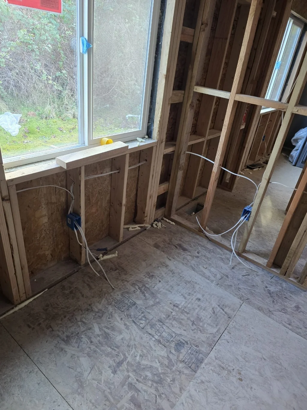 Electrical boxes and rough-in wiring in open wall framing by a window during a Mount Vernon, WA remodel