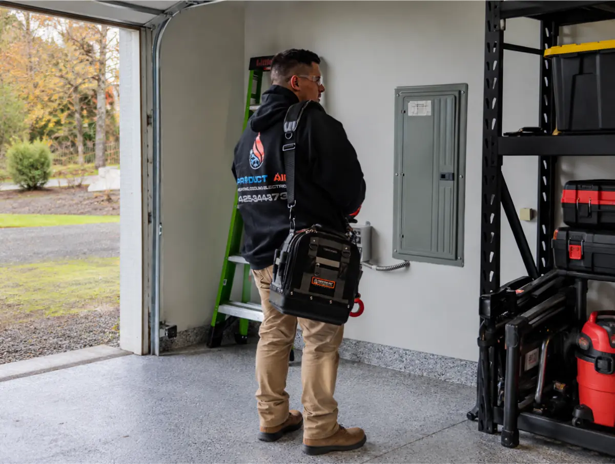 Electrician inspecting a residential electrical panel in a garage.