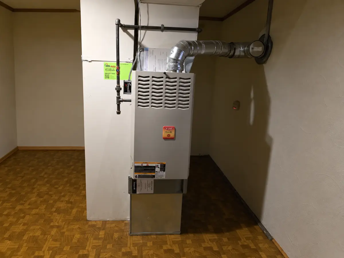 Residential gas furnace with metal vent pipe and ductwork installed indoors.