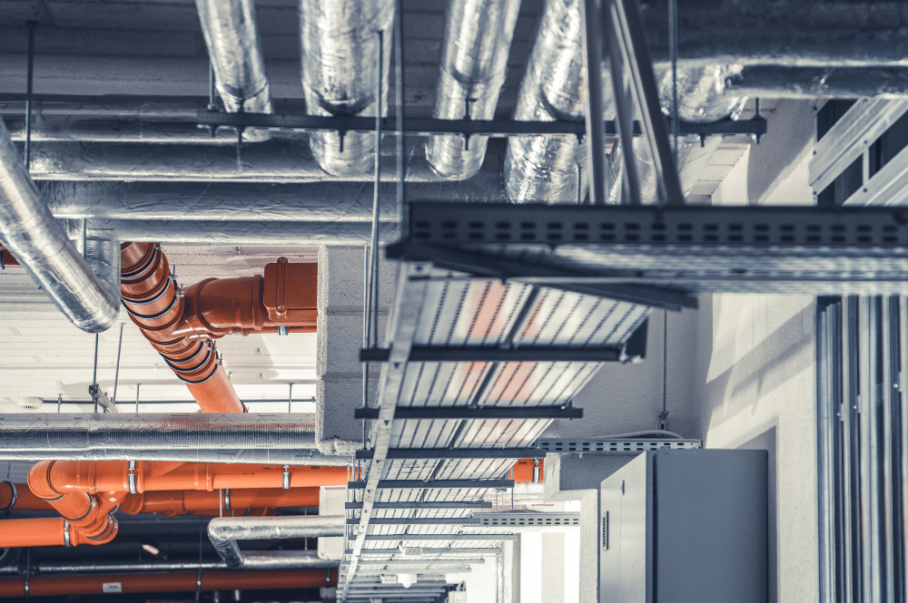 Interior of a building showcasing a commercial heating system upgrade with a network of orange and white pipes.